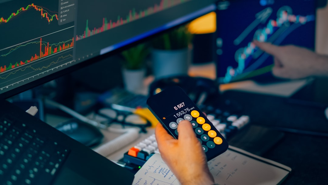 hero-img-01 Financial trading workstation stock crypto investment analysis. Closeup hand holding smartphone calculator desk monitors charts candlesticks graphs market data savings portfolio planning risk management economy finance technology office night lighting focus strategy performance growth profit volatility currency bitcoin ethereum exchange dashboard indicators keyboard notebook calculations